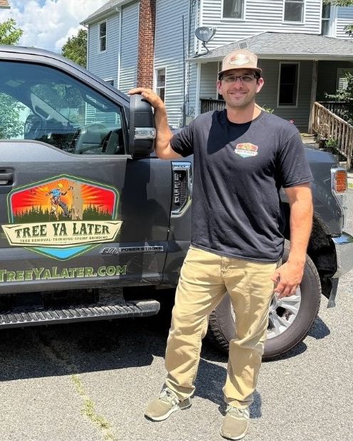 A Tree Ya Later team member standing beside the company pickup truck
